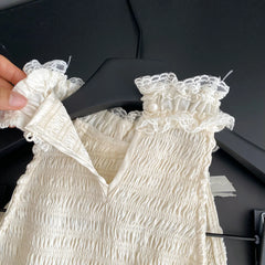 White lace-trimmed dress on a black hanger against a dark background