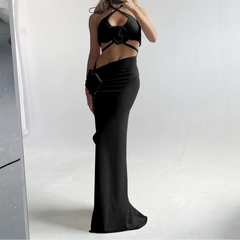 Person wearing a black dress with cut-out design and a white hat, standing in front of a mirror.