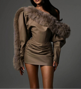 Woman wearing a beige dress with fur shoulders against a gray background