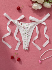 White lace thong with cherry pattern on a pink background with ribbons and cherries.