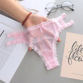 Pink lace lingerie held by a hand on a surface with books and glasses.
