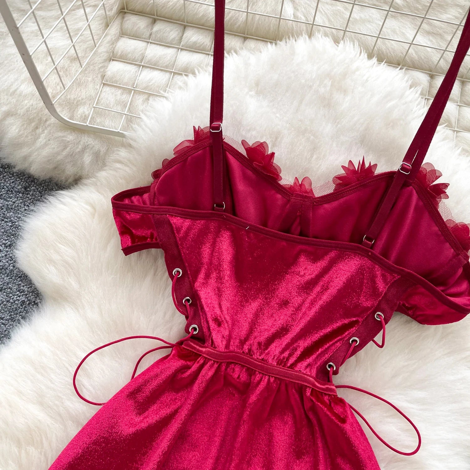 Red velvet dress with floral straps on a white textured surface