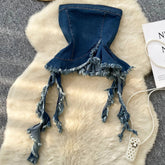 Denim bikini top with tassels on a fur surface with a hat and card in the background