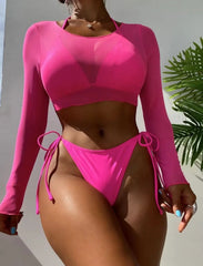 Person wearing a bright pink long-sleeve bikini set against a neutral background with a plant.