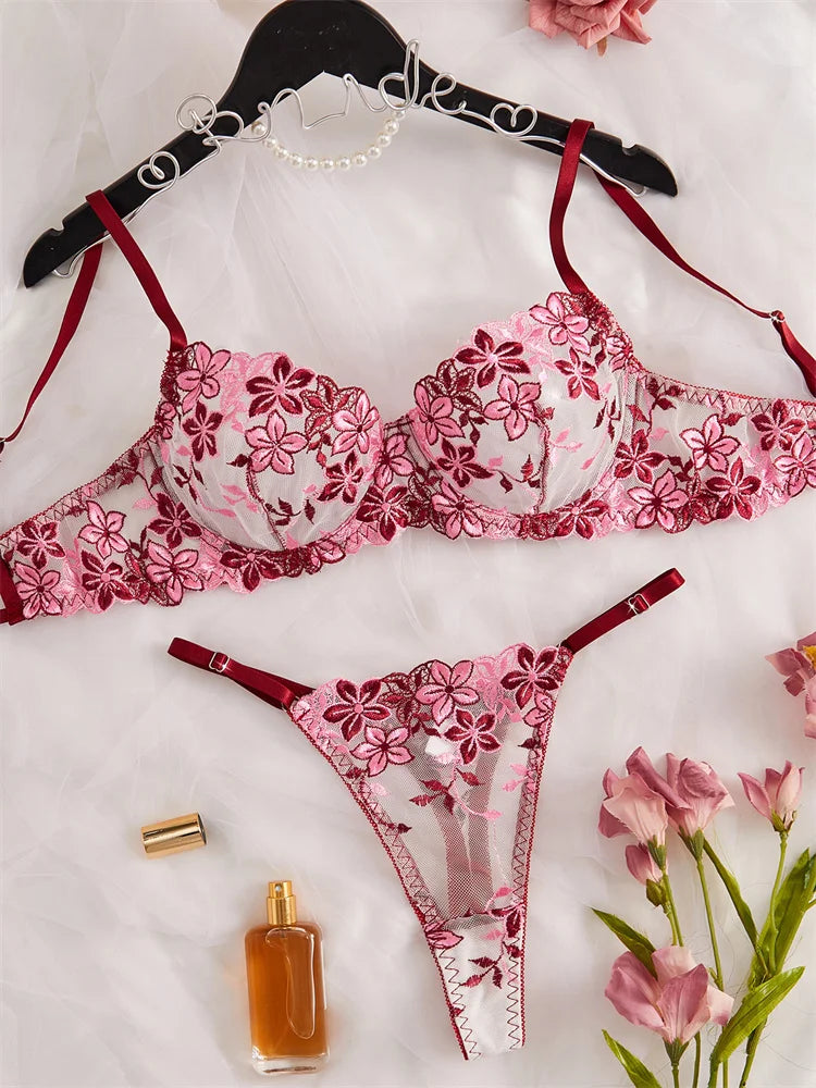 Pink floral lingerie set with a perfume bottle and flowers on a light background