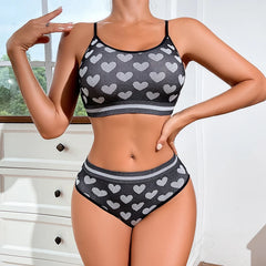 Person wearing a black sports bra and high-waisted underwear with heart pattern in a bright room.
