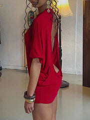 Person wearing a red dress with cut-out design in an indoor setting.