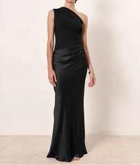 Woman wearing a black one-shoulder gown against a plain background