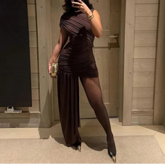 Woman taking a mirror selfie wearing a brown dress in a room with wooden walls.