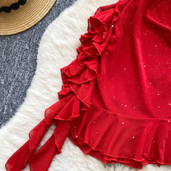 Red ruffled garment on a textured surface with a straw hat in the background