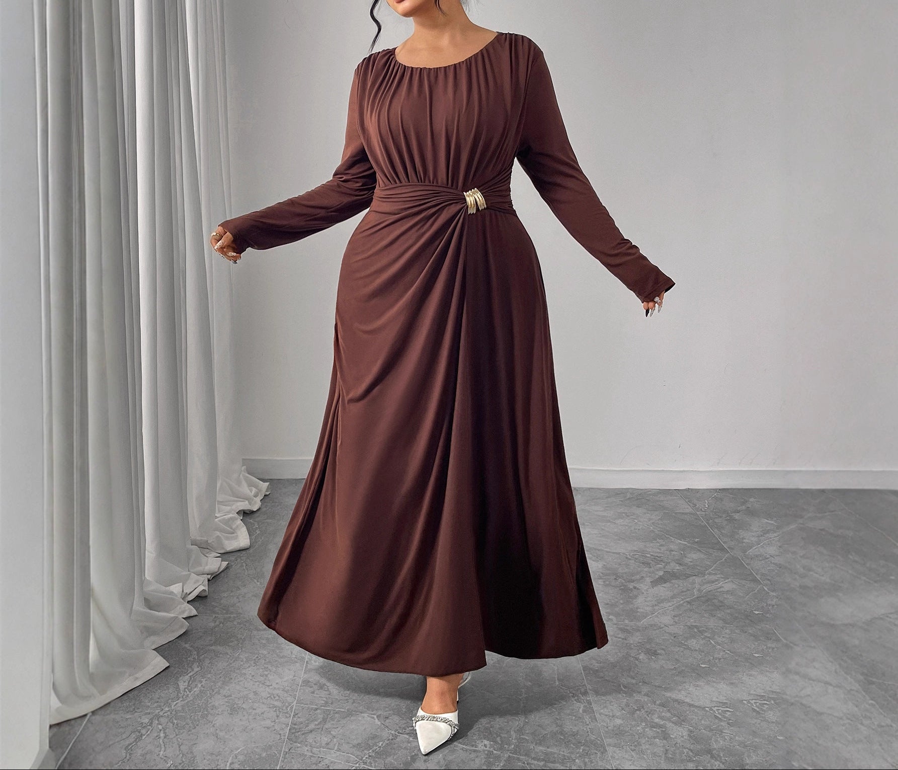 Woman wearing a brown long-sleeve dress in a minimalistic setting