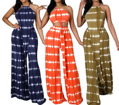 Three women wearing tie-dye jumpsuits in blue, orange, and green on a white background.