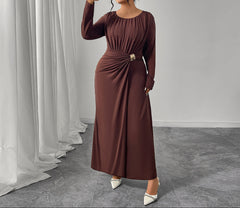 Woman in a brown dress taking a selfie in a room with white curtains and gray floor.