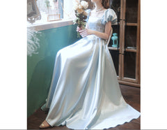 Woman in a white dress holding flowers by a window