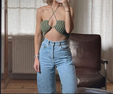 A person wearing a green knitting sleeveless crop top and blue jeans, taking a mirror selfie.