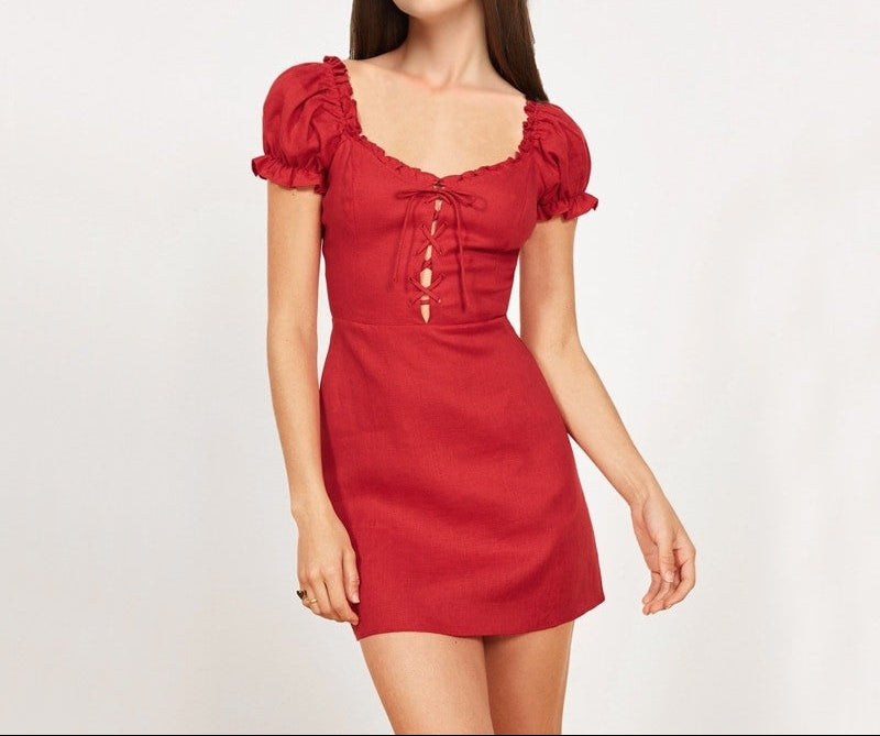 A woman wearing a red vintage lace mini dress with a square collar, lantern sleeves, and a button-up front.