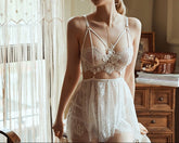 A woman wearing white backless sleepwear with floral lace and a V-neck collar, above knee length, in a room with a light interior.