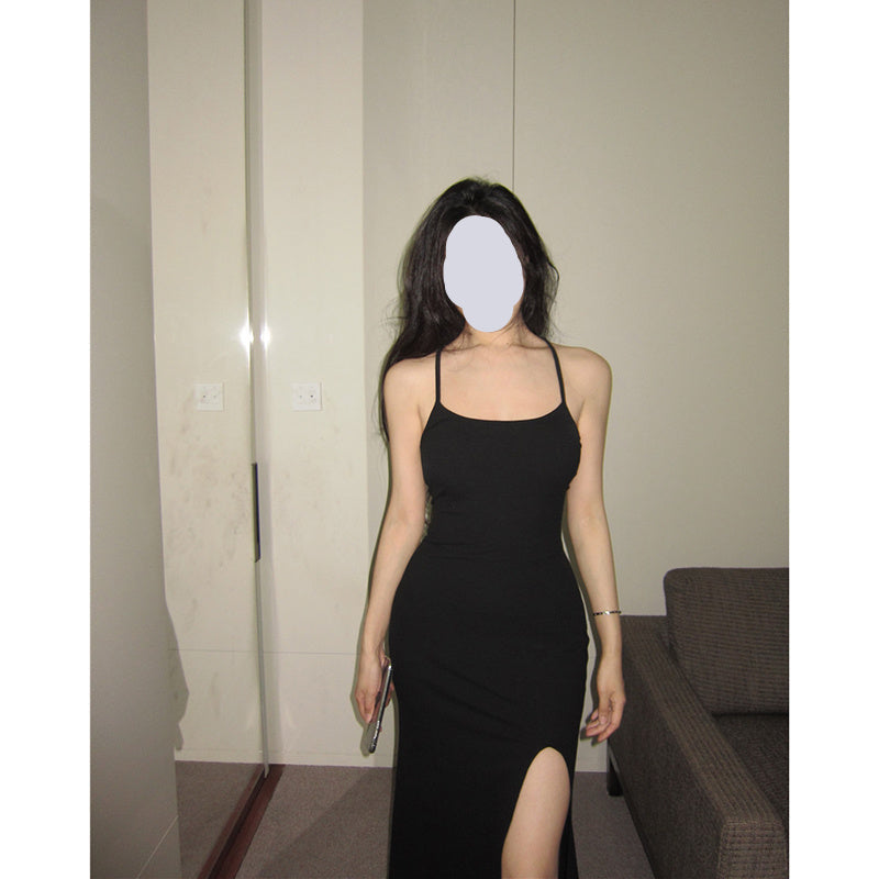 Woman wearing a black dress standing in a room with neutral walls and a couch.