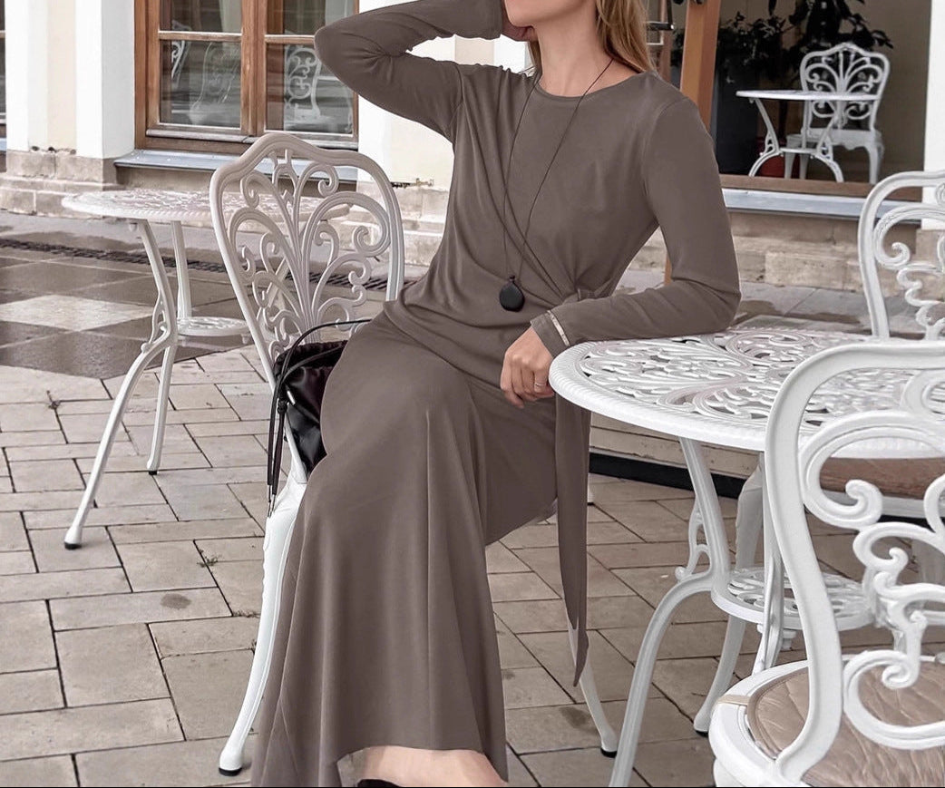 Woman in a brown dress sitting at an outdoor cafe table.