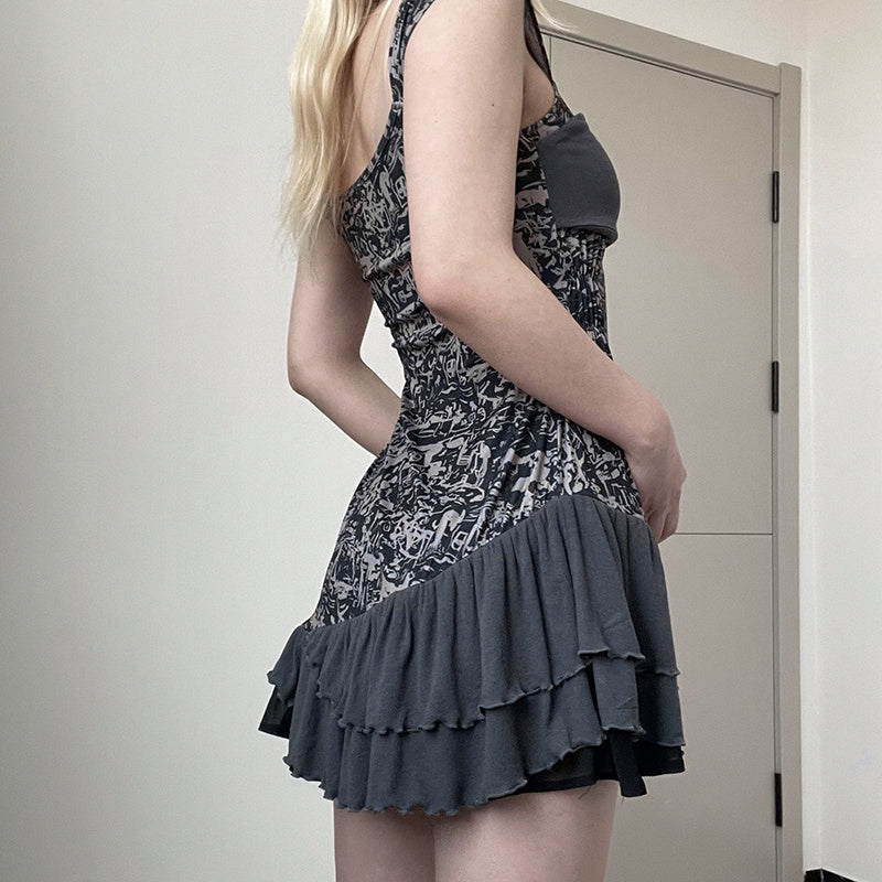 Person wearing a patterned dress with ruffled layers in front of a plain wall.