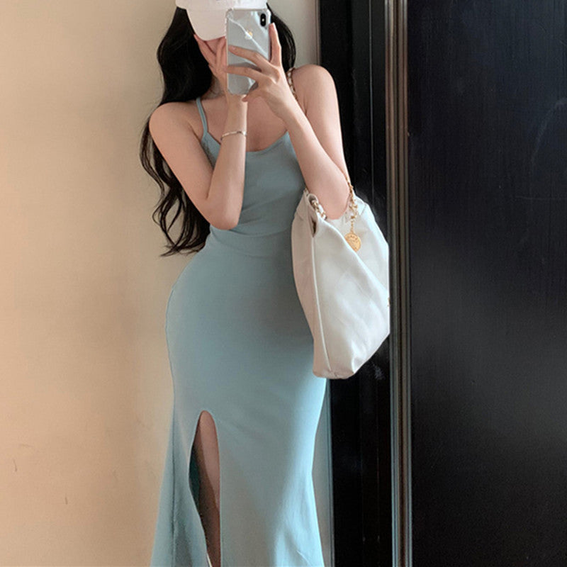 Woman in a light blue dress taking a mirror selfie with a white handbag.