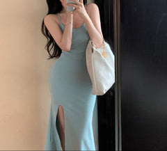 Woman in a light blue dress taking a mirror selfie with a white handbag.
