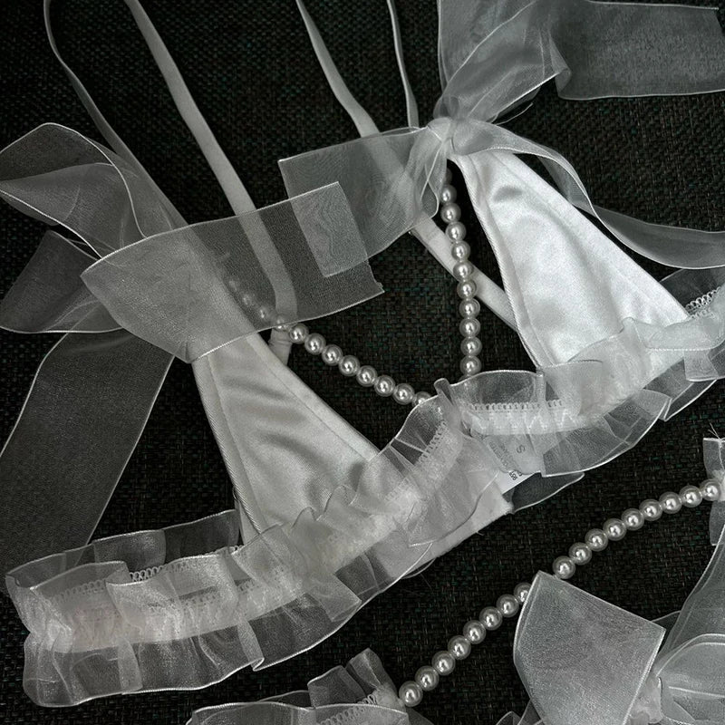 Pearl necklace draped over sheer ribbons on a black background