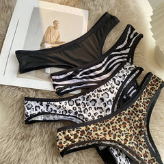 Four women’s G-strings in solid black, stripes and animal prints arranged on a neutral surface.