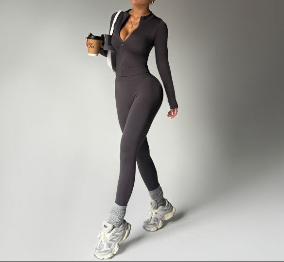 Woman in a gray athletic outfit holding a coffee cup on a plain background