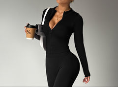 Woman in a black outfit holding a coffee cup against a gray background