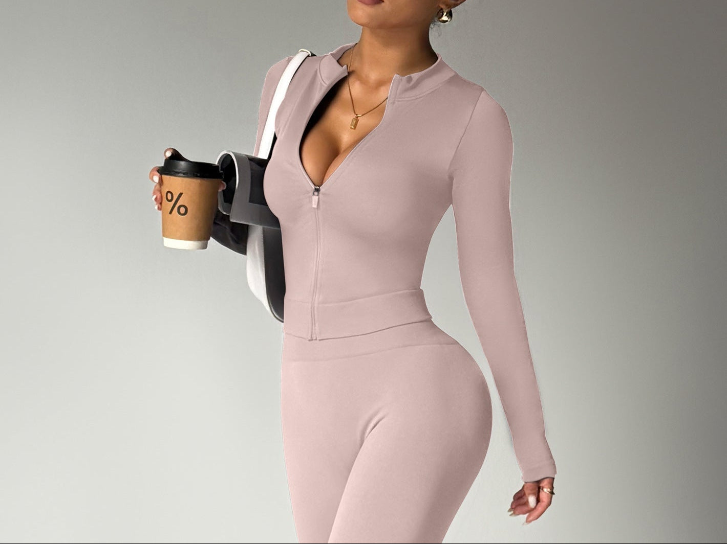 Woman in a pink jumpsuit holding a coffee cup against a gray background