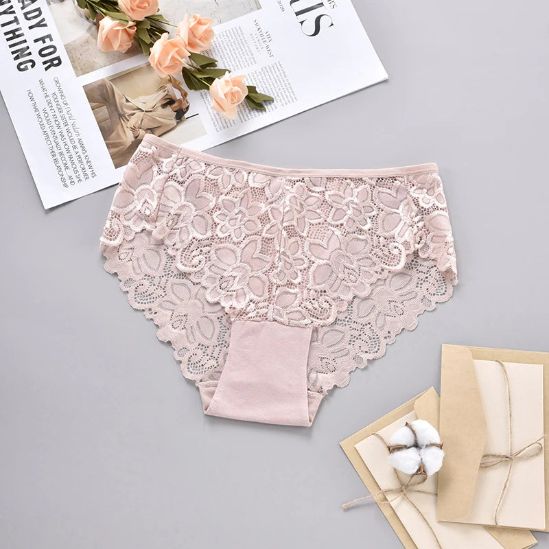 Pink lace underwear on a gray surface with flowers and a magazine.