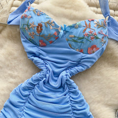 Blue mermaid tail with floral embroidery on a beige surface