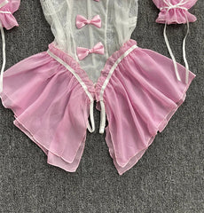 Pink and white baby outfit with ruffles and bows on a gray background