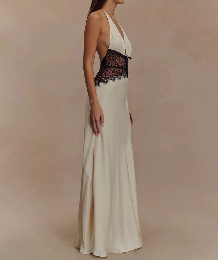 Woman wearing a white evening gown with black lace details on a beige background