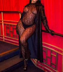 Person wearing a black leopard print bodysuit and sunglasses against a red curtain background