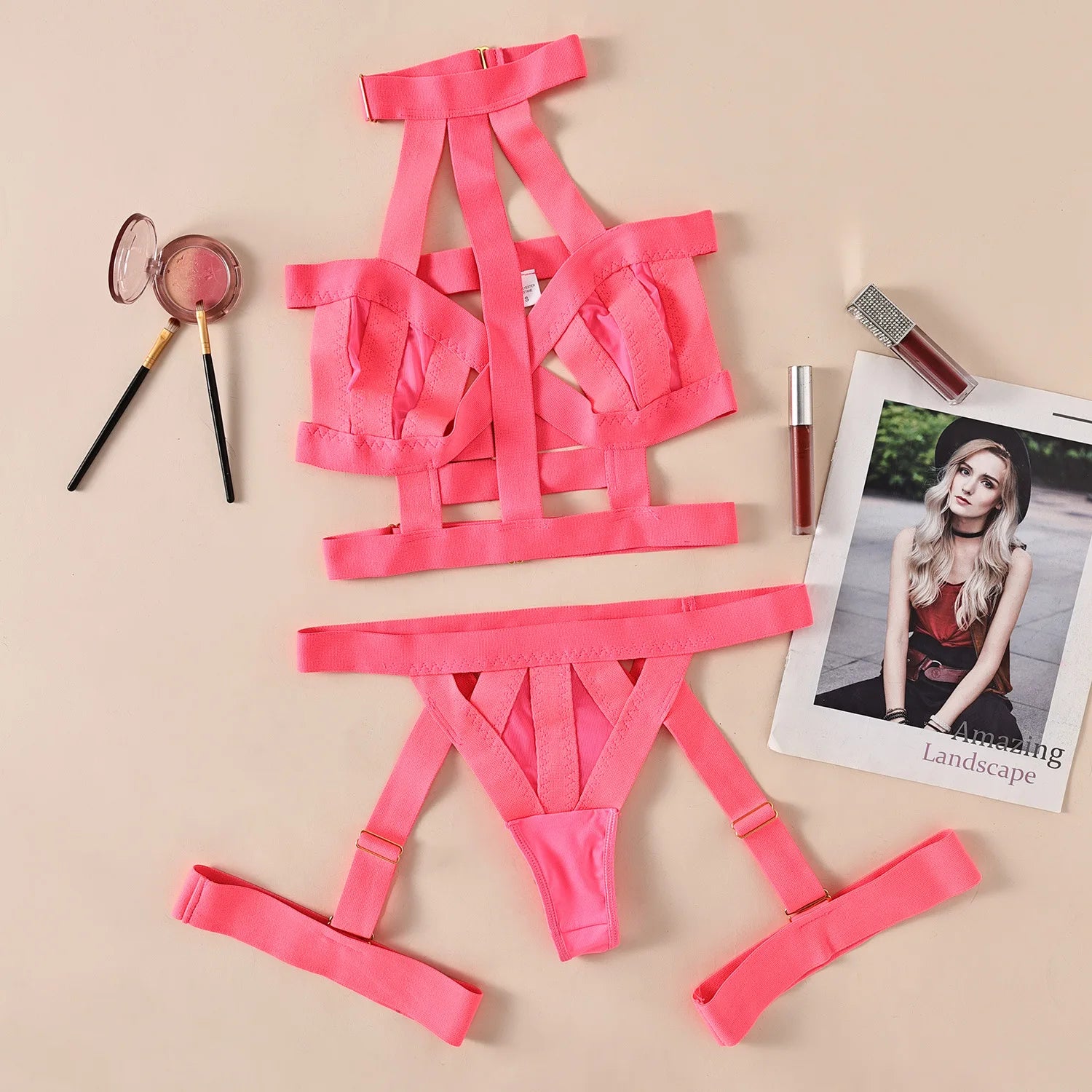 Pink strappy garment on a beige background with makeup and a magazine.