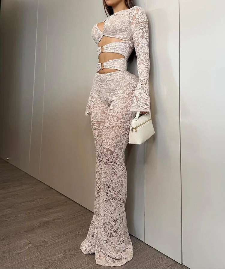 Woman in a white lace outfit standing against a neutral wall.