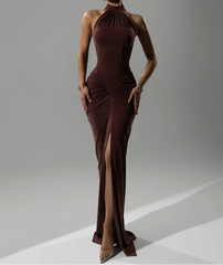 Woman wearing a brown evening gown with a high slit on a gray background