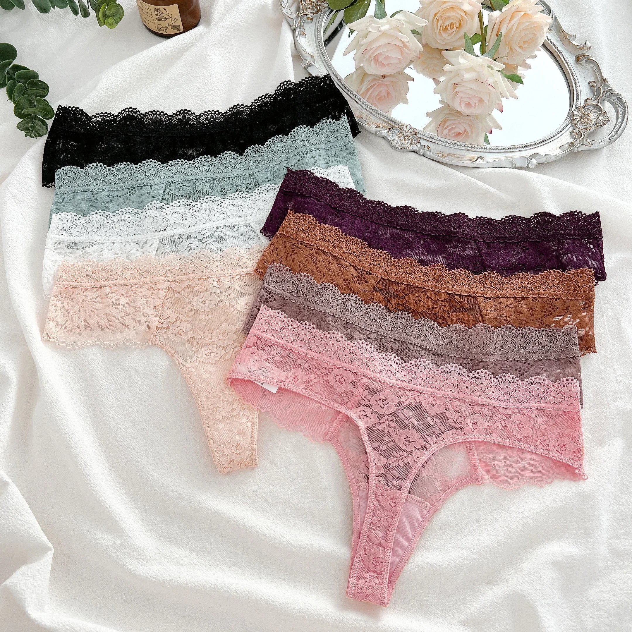 Set of lace-trimmed panties in various colors on a white fabric background.