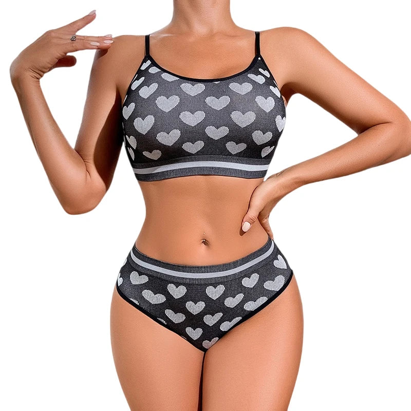 Woman wearing a black sports bra and high-waisted underwear with heart pattern on a white background