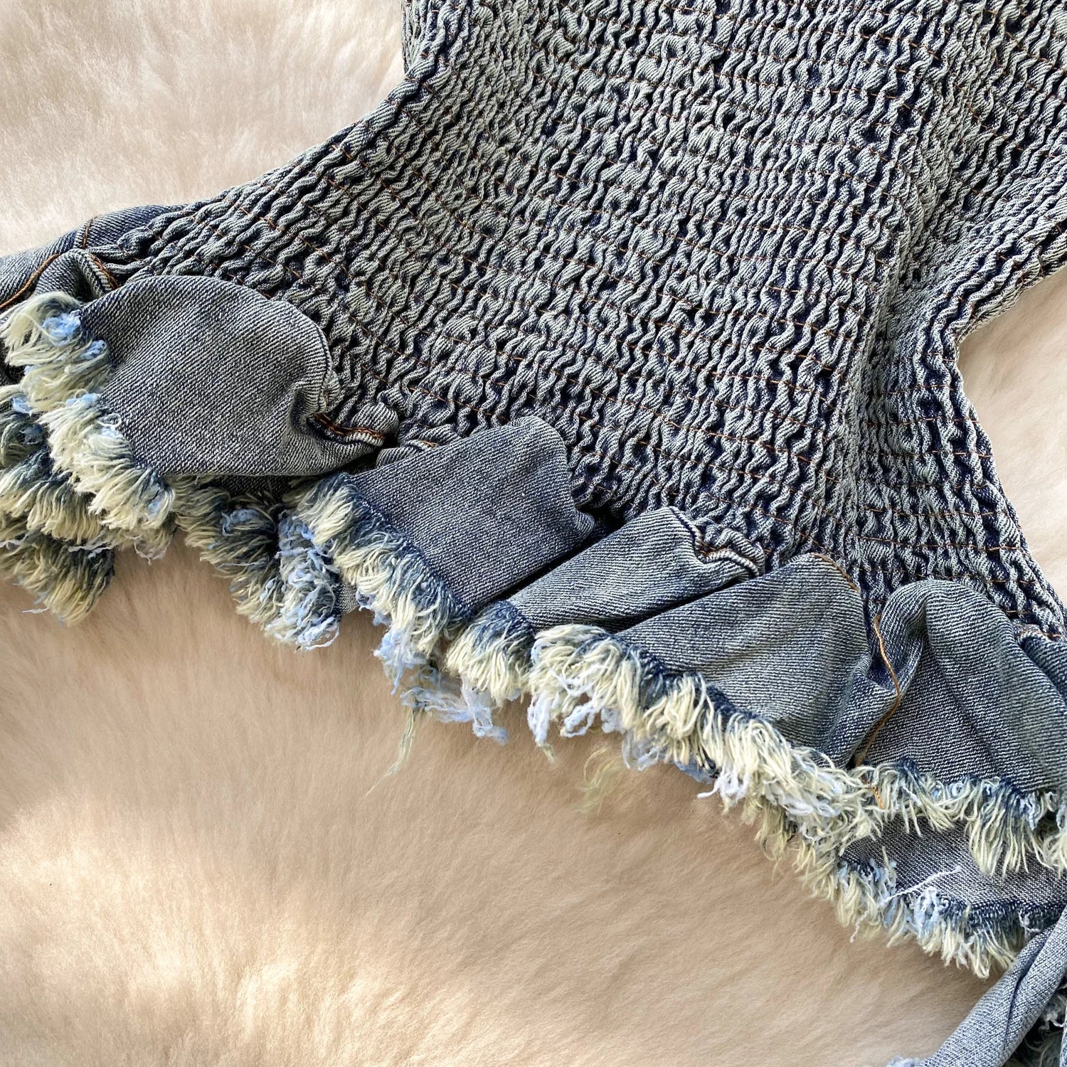 Textured blanket with frayed edges on a beige surface
