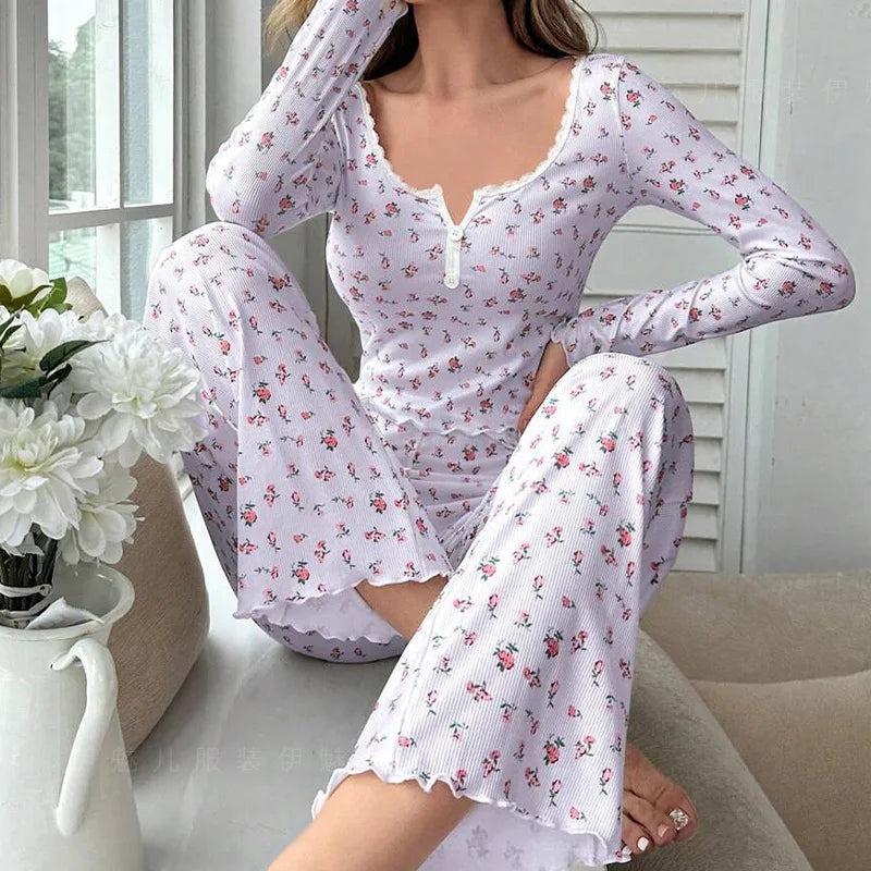 Woman wearing a white floral pajama set sitting on a couch with flowers in the background.