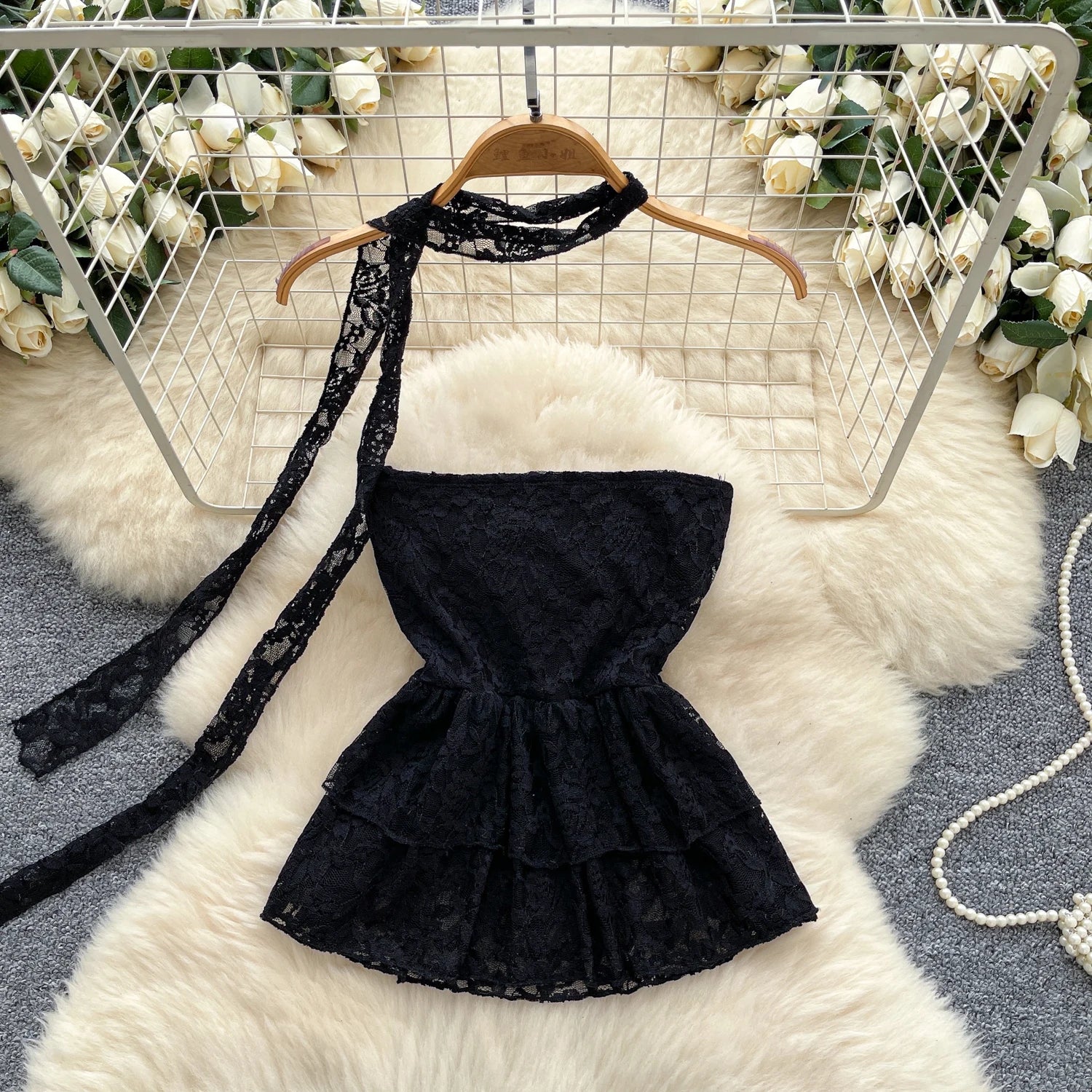 Black lace dress on a hanger with floral decorations in the background