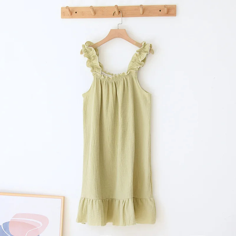Light green dress with ruffled details on a wooden hanger against a white wall.