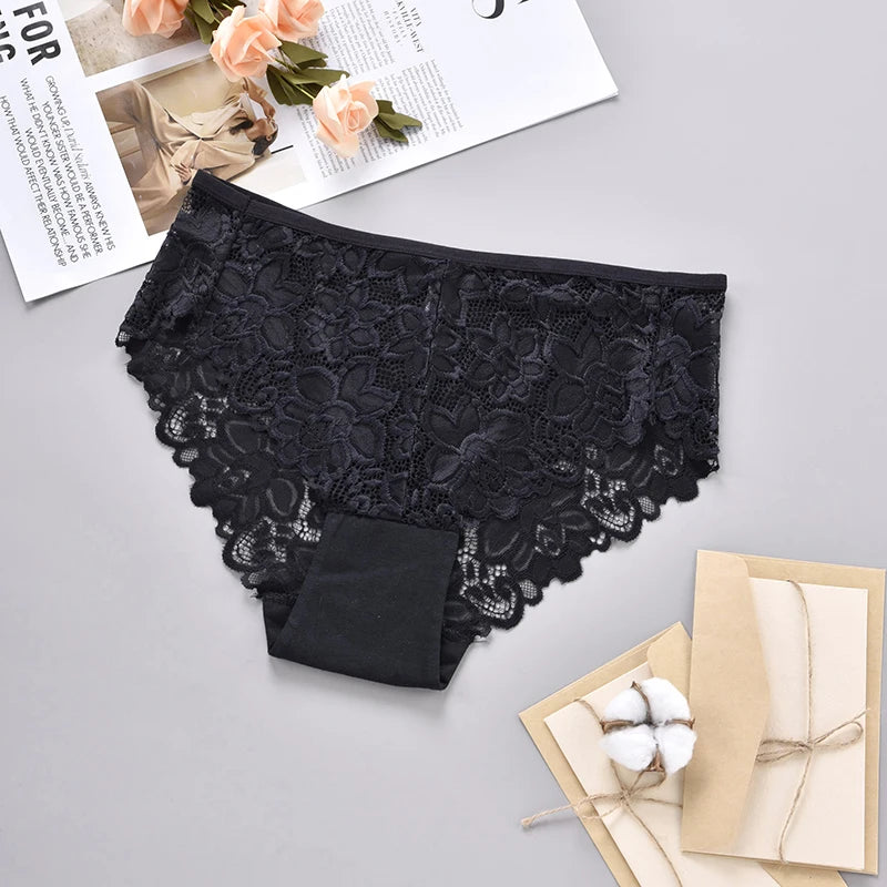 Black lace underwear on a gray surface with a magazine and gift box in the background