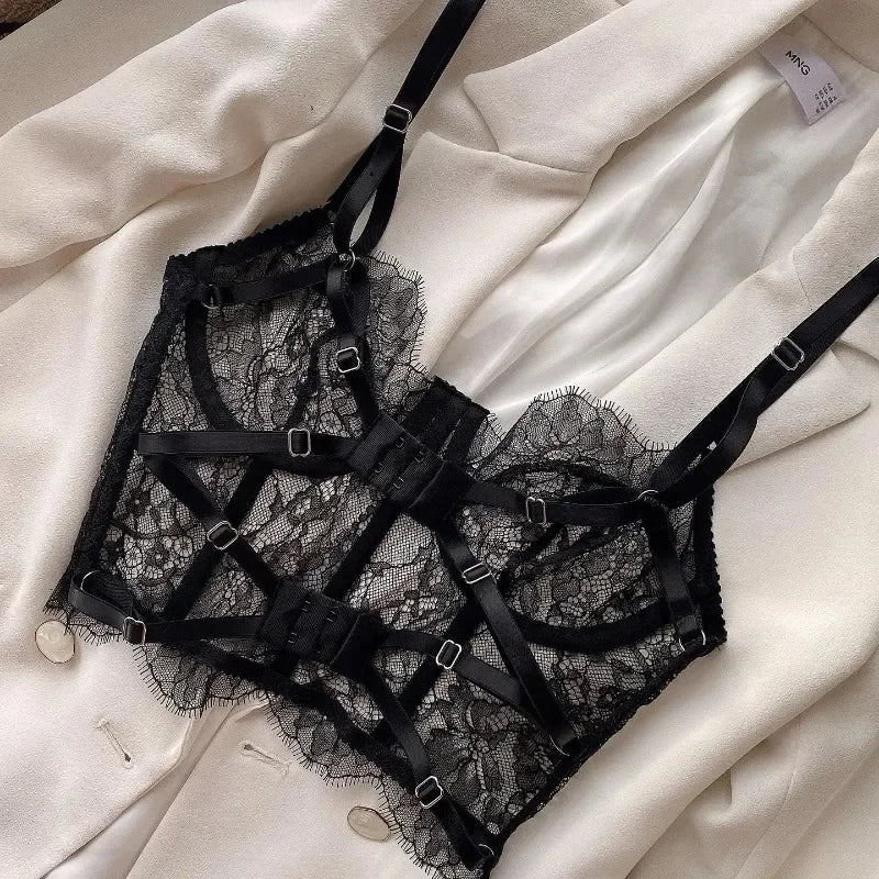 Black lace lingerie set with straps on a white fabric background