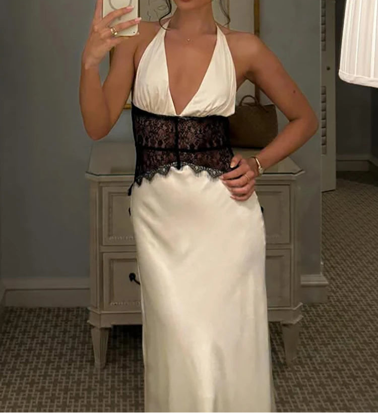 Woman taking a mirror selfie wearing a white halter top and black lace bodice with a long white skirt.