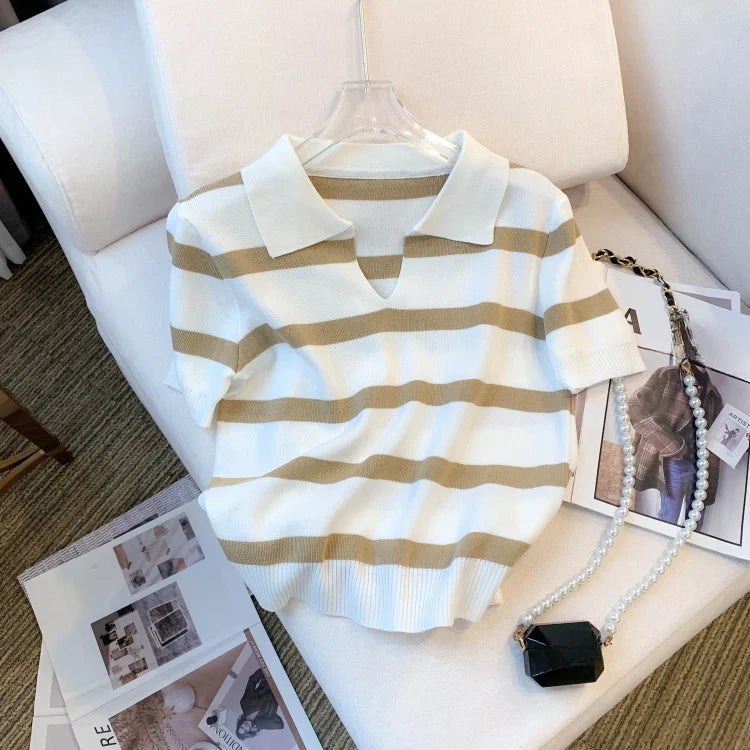 Striped shirt on a hanger with a black handbag and photo album on a white surface.