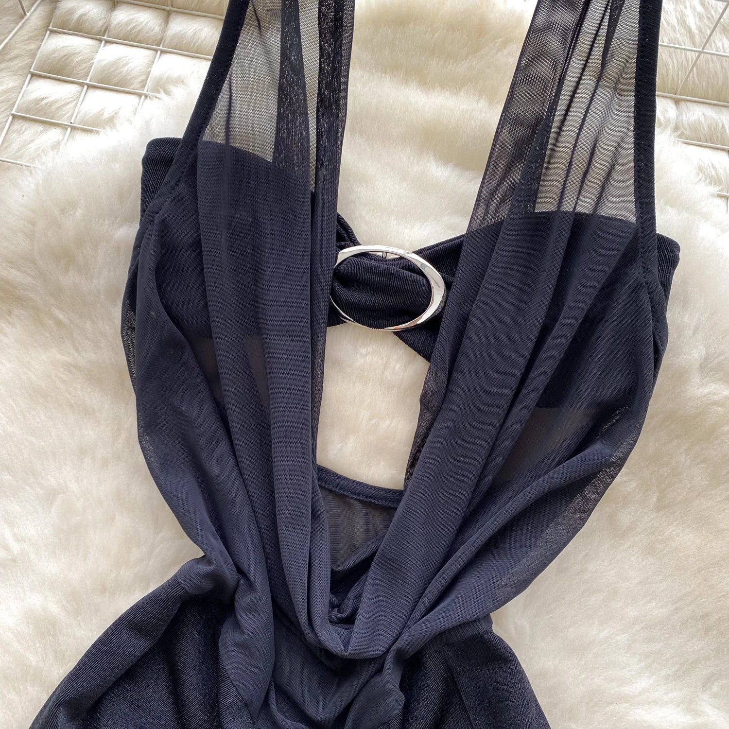 Navy blue dress with sheer overlay on a textured white surface
